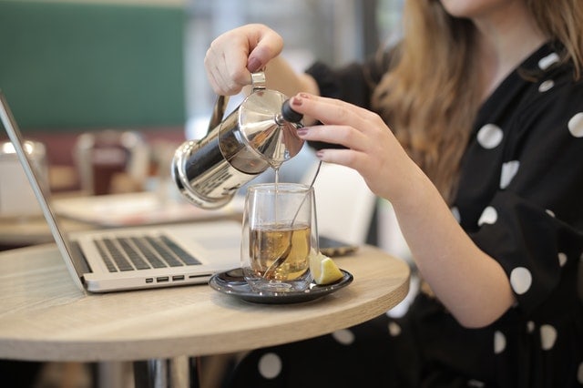 woman pouring hot decaf green tea into a glass