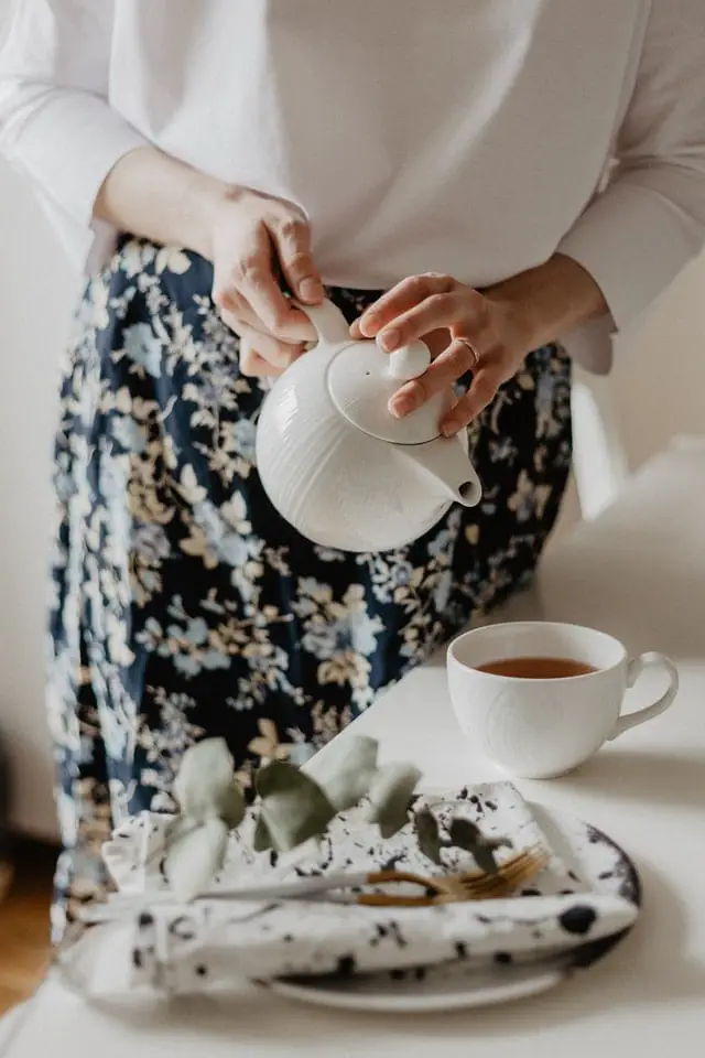 Woman Adding Milk To Tea