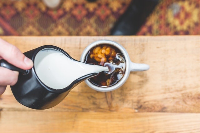 Person Pouring Milk To Tea