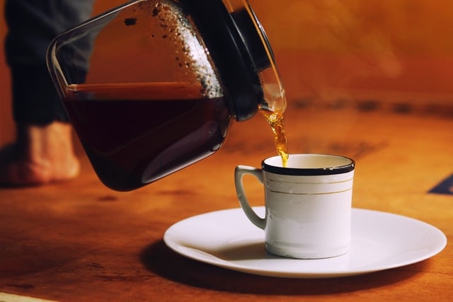 Pouring Hot Tea Into White Cup and Saucer