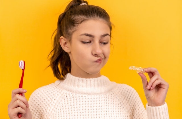 Girl Holding A Tooth Brush and A Retainer