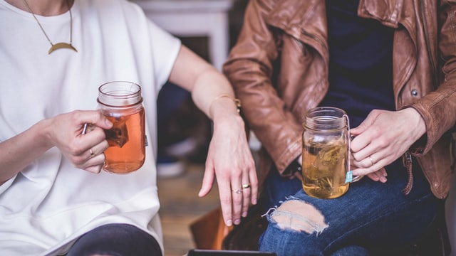 Two people sitting while holding a cup of tea