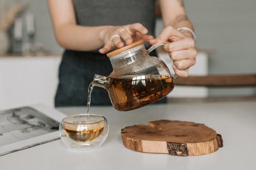 Lady Pouring Black Tea From Glass Tea Pot