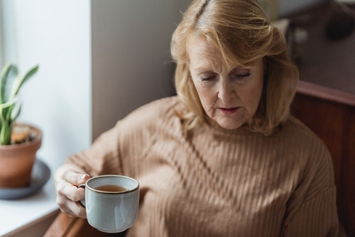 Old Lady Drinking Tea Sitting Near the Window