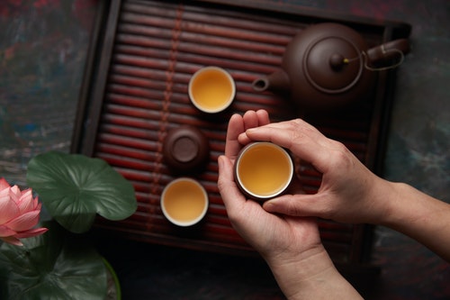 Person holding green tea served in brown ceramic cups