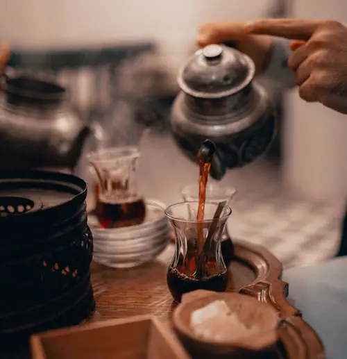 Person pouring tea from antique teapot