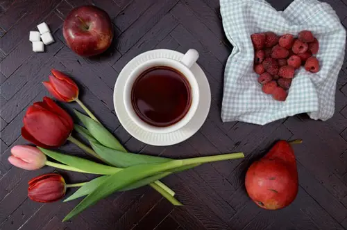 Fresh raspberry tea along with red fruits and flowers